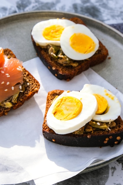 Toasted breads with boiled eggs, avocado and salmon. Guacamole sandwiches. Healthy breakfast. Sesame seeds. Vegetarian healthy eating.