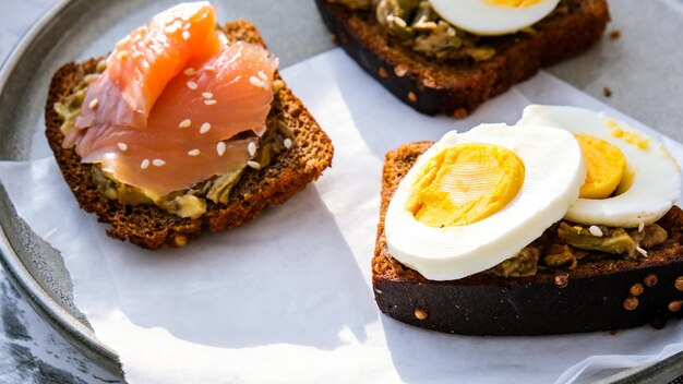 Toasted breads with boiled eggs, avocado and salmon. Guacamole sandwiches. Healthy breakfast. Sesame seeds. Vegetarian healthy eating.