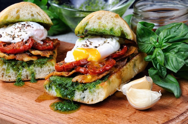 Toasted ciabatta with pesto slices of bacon sundried tomatoes and poached egg