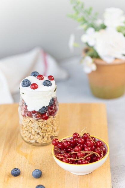 Toasted muesli or homemade granola with nuts and yogurt and berries in small glass jar