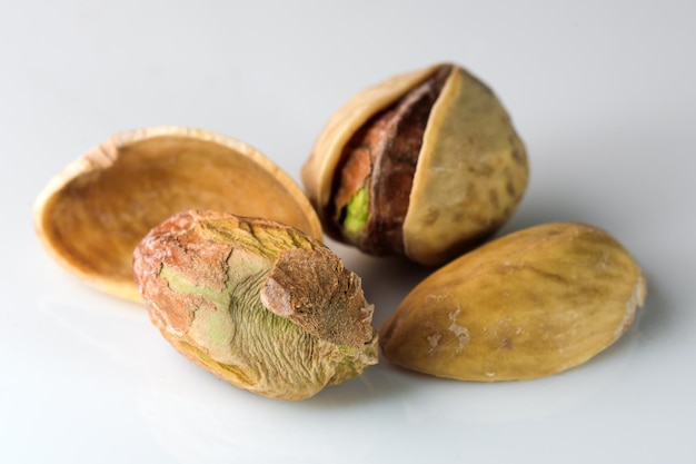 Toasted salted pistachio nuts on white reflective background close-up macro photography