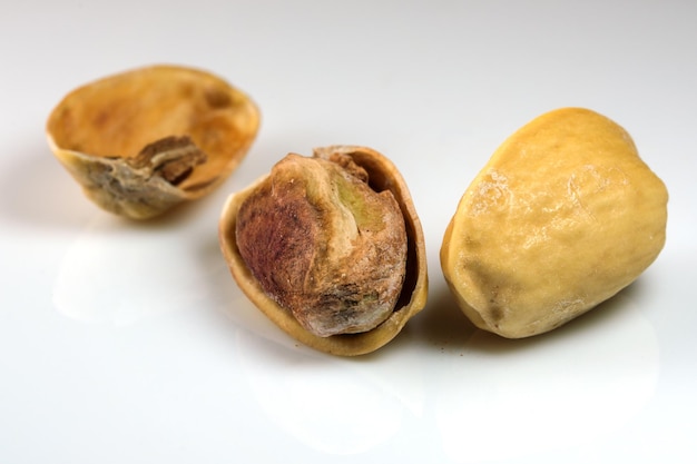 Toasted salted pistachio nuts on white reflective background close-up macro photography