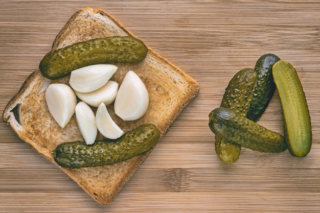 Toasted sandwich with pickles and young fresh garlic on a wooden board