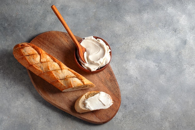 Toasted sliced garlic bread baguette with cottage cheese served on cutting board with blue linen napkin on gray stone background bakery conceptxA