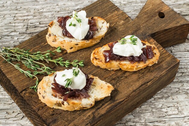 Toasted slices of baguette with onion jam cream cheese and thyme