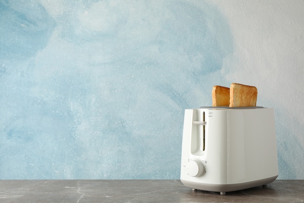 Photo toaster with bread slices on blue background, space for text