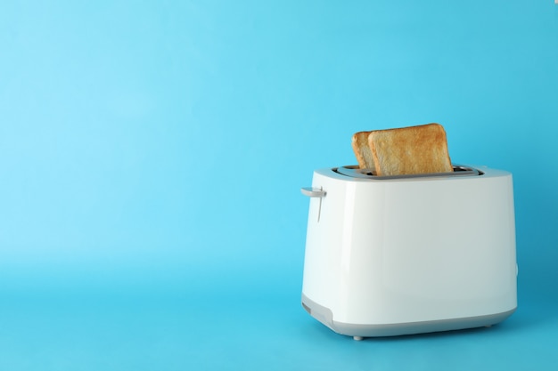 Photo toaster with bread slices on blue background, space for text