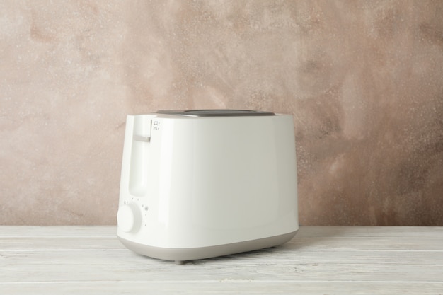 Toaster on wooden table against brown background, space for text