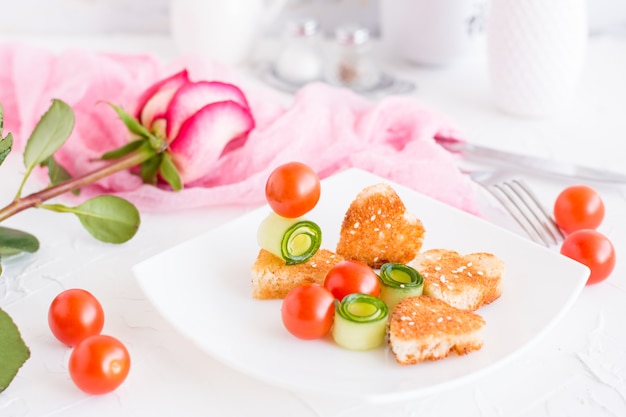 Toasts in the form of heart and vegetables on a plate