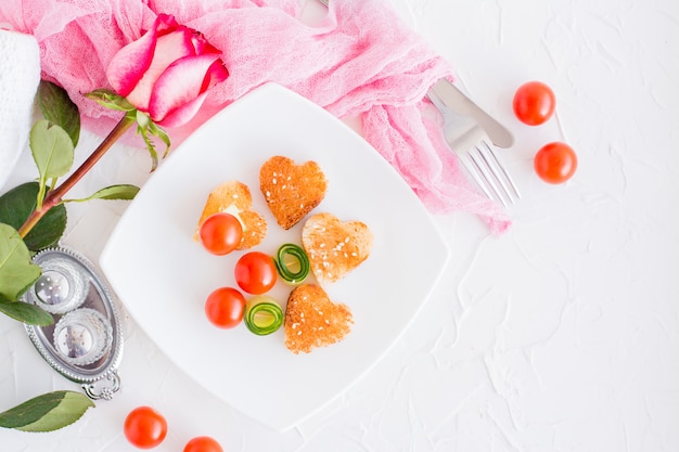 Toasts in the form of heart and vegetables on a plate