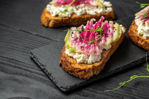Toasts from sliced watermelon radish with chinese daikon cottage cheese and microgreen Food recipe background Close up