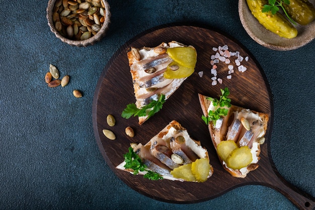 Toasts with bread herring pickled cucumber and cream cheese Smorrebrod with herring Danish food Sandwich with herring Healthy breakfast