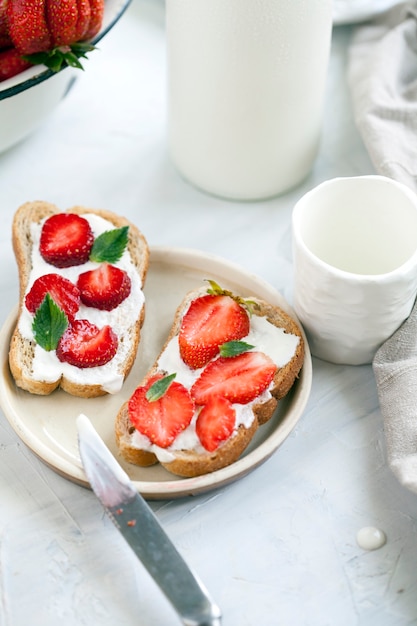 Photo toasts with cheese cream and slices of strawberries.