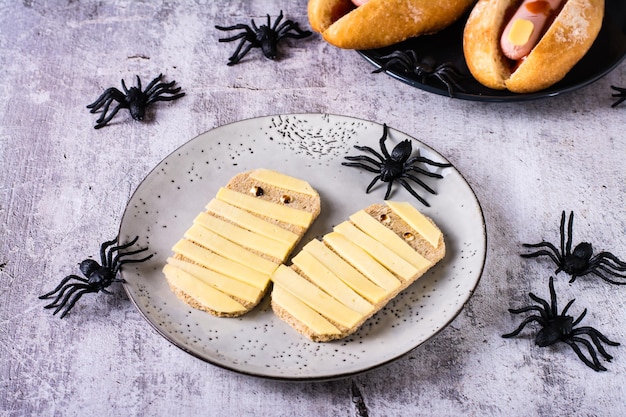 Foto brindisi con formaggio sotto forma di mummie su un piatto e ragni ricetta di halloween