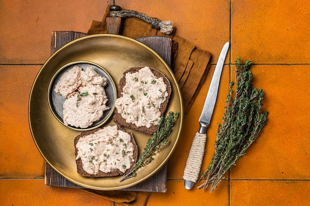 Toasts with Cod liver Spread pate on a plate Orange background Top view