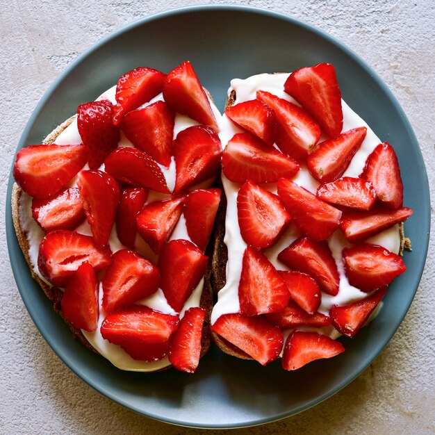 Toasts with cottage cheese and ripe strawberries on a plate