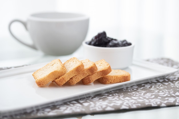 Toasts with cranberries jam and a cup of coffee on white