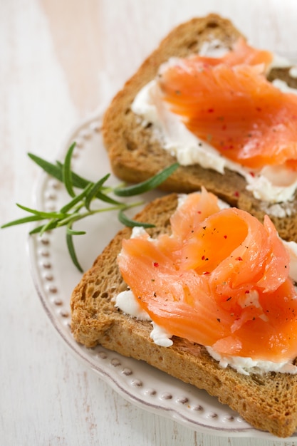 Toasts with cream cheese and smoked salmon on white plate