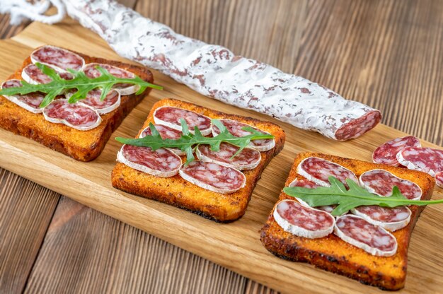 Toasts with fuet on the wooden board