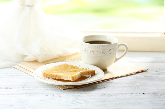 Toasts with honey on plate with cup of tea on bright background