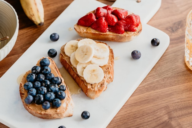 Toasts with peanut butter blueberry strawberry and banana Healthy breakfast concept