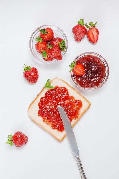 Toasts with strawberry jam for breakfast on white rusric wooden background Top view