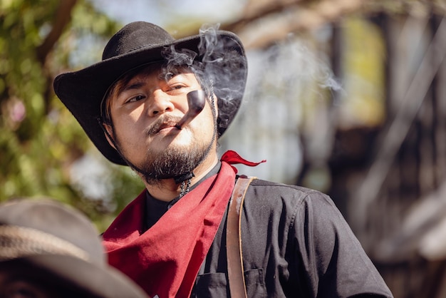 A tobacco pipe is smoked by a cowboy wearing a widebrimmed hat and a headband