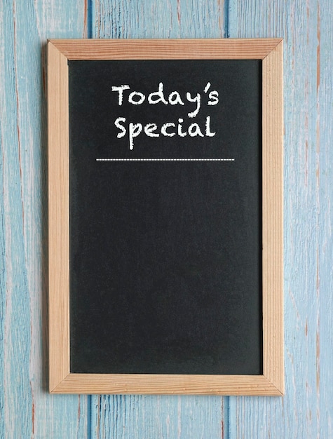 Photo today's specials words in white chalk on a blackboard isolated on blue wood