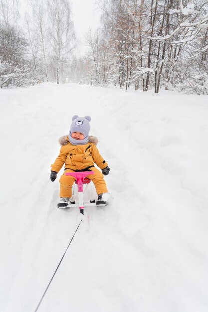 生後1217か月の幼児が、両親の1人がロープで引っ張る子供用雪上車に乗る