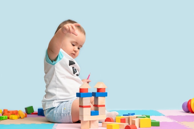 Toddler 1217 months playing with a designer of colorful wooden cubes sitting on the floor in the playroom