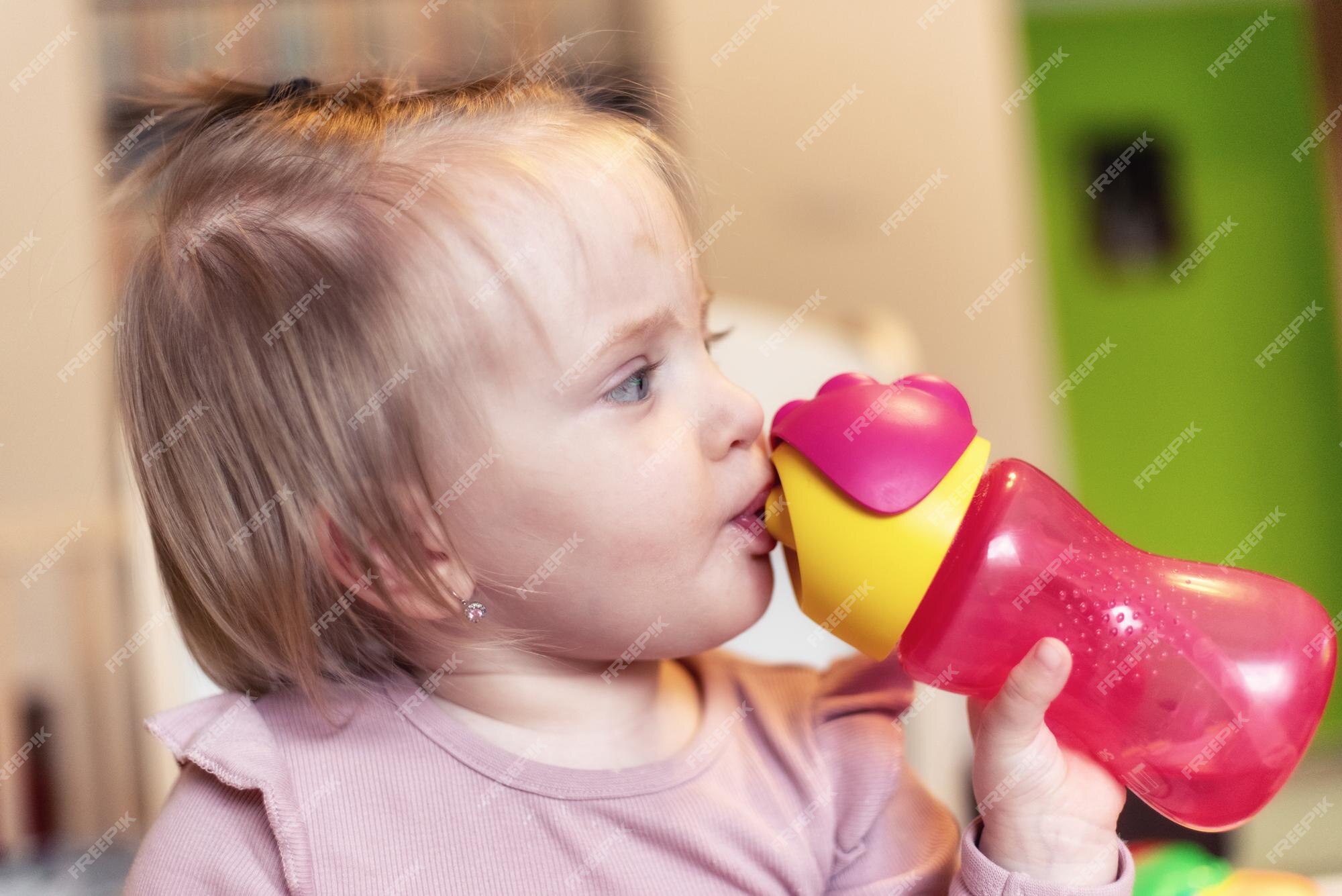 Toddler girl drinking water from the baby bottle Stock Photo