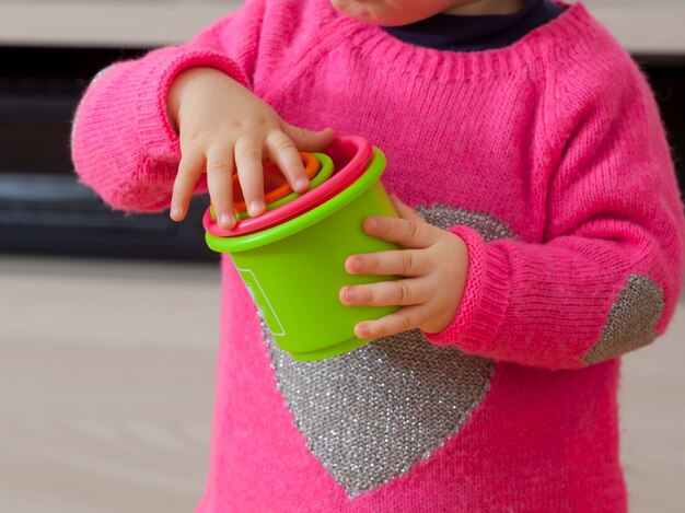 Toddler baby girl plays with colored cups