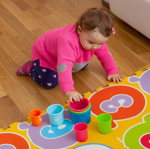 Toddler baby girl plays with colored cups