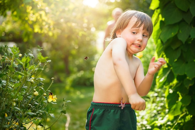 夏に飛んでくるマルハナバチをかわす幼児の少年 ミツバチを恐れる感情的な子供 昆虫恐怖症