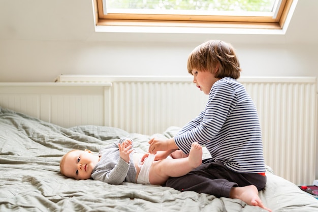 Toddler boy helping to change diaper to his sibling Little mother's helper caring older brother