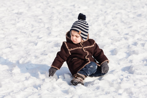 Toddler boy is walking on the snow-covered ground