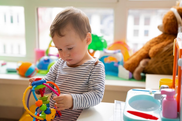 Toddler boy plays with educational toys in the children's room The study of colors and the development of tactility Child one and a half years two years Selective focus