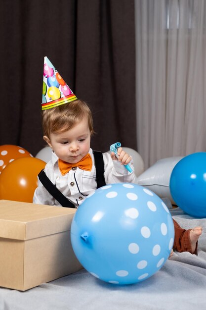Маленький ребенок празднует свой первый день рождения среди воздушных шаров