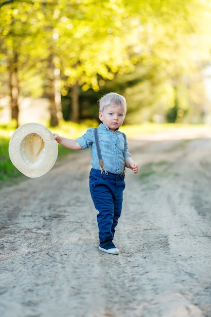 Toddler child outdoors rural scene with one year old baby boy with straw hat