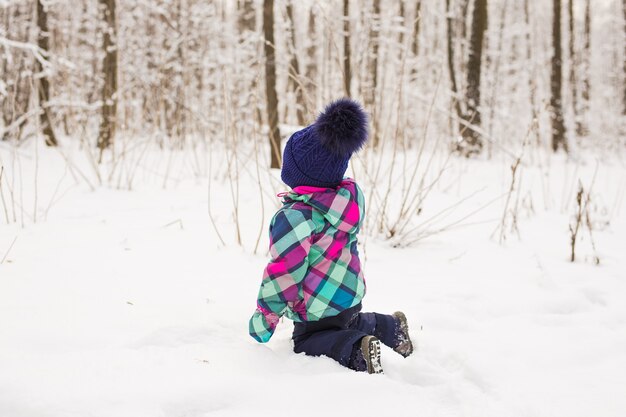 Toddler child playing in a snow in winter.