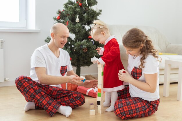 Toddler child with cochlear implant plays with parents under christmas tree deafness and innovating medical technologies for hearing aid and diversity