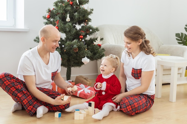 Toddler child with cochlear implant plays with parents under christmas tree deafness and innovating medical technologies for hearing aid and diversity