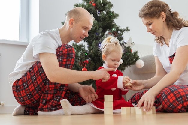 Toddler child with cochlear implant plays with parents under christmas tree deafness and innovating medical technologies for hearing aid