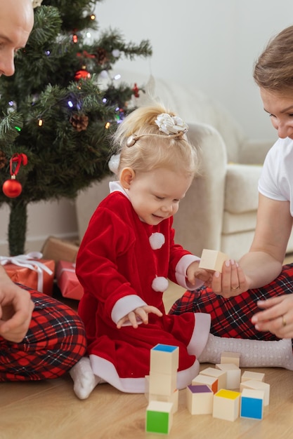 人工内耳を持つ幼児の子供は、クリスマスツリーの難聴と補聴器のための革新的な医療技術の下で両親と遊ぶ