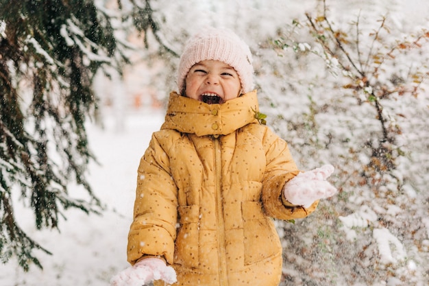 冬の雪の日に幸せな幼児の女の子。クリスマス休暇に外で遊ぶ