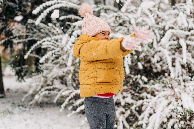 冬の雪の日に幸せな幼児の女の子。クリスマス休暇に外で遊ぶ