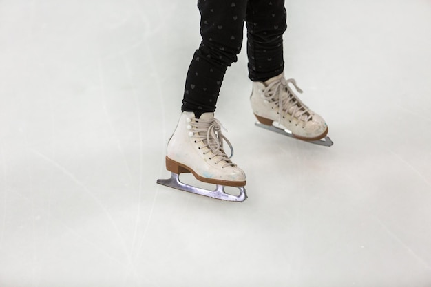 Toddler girl learning how to ice skate on in door ice arena.