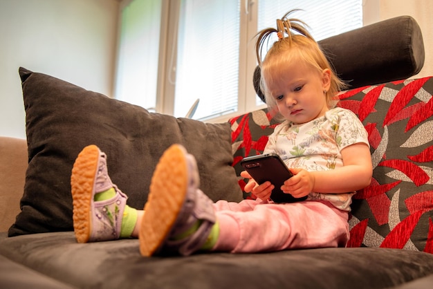 幼児の女の子が座ってスマートフォンを保持