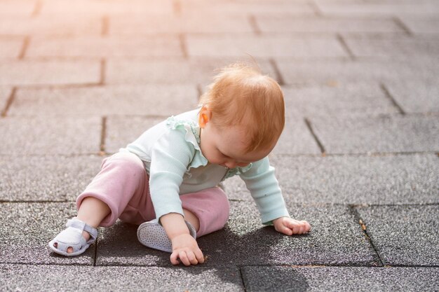 遊び場の表面に座っている幼児の女の子が葉っぱを見つける