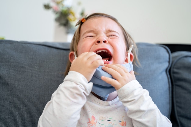 顔に医療マスクを持つ幼児の女の子。コロナウイルスの発生